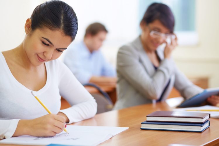 Portrait of pretty girl sitting in college library and making notes